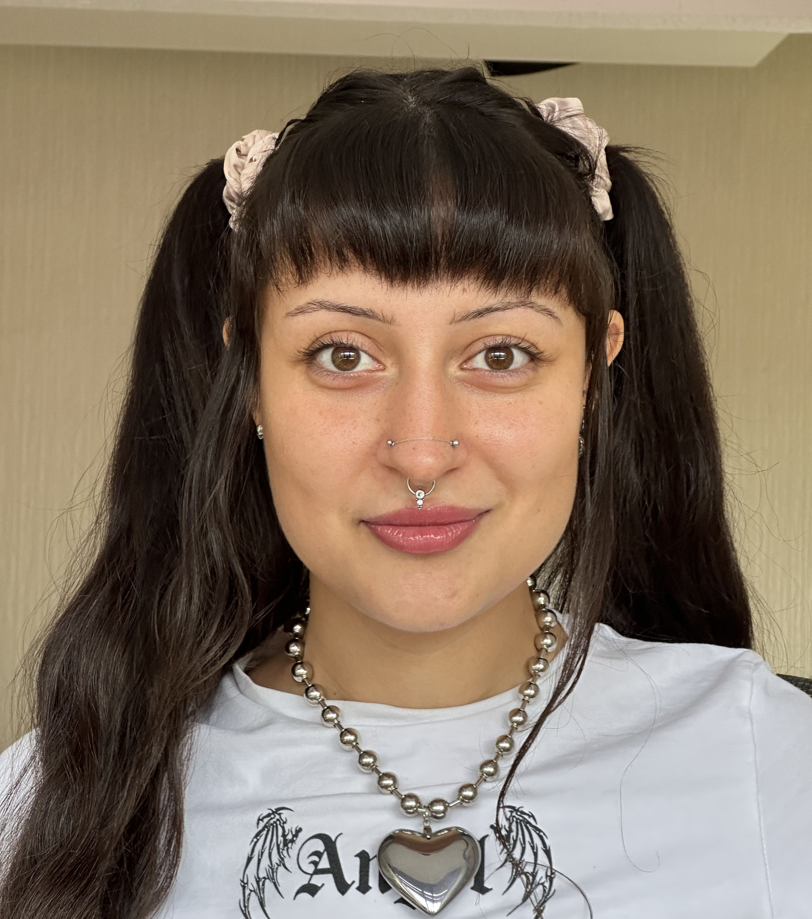 Mars has long dark hair and is wearing a t-shirt with a heart necklace.